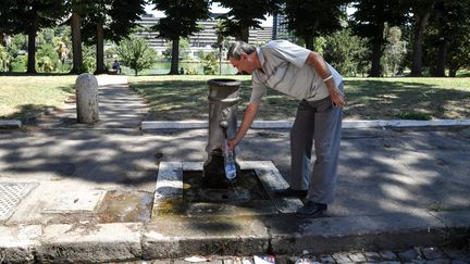 Un homme remplit une bouteille d'eau dans une fontaine à Rome (Italie), le 6 juillet 2017. (ANDREAS SOLARO / AFP)