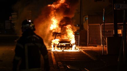 Un pompier devant une voiture en feu à Bordeaux, en Gironde, le 29 juin 2023. (PHILIPPE LOPEZ / AFP)