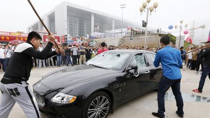 Des hommes engag&eacute;s par le propri&eacute;taire d'une Maserati d&eacute;truisent le v&eacute;hicule &agrave; coup de marteau afin de protester contre les faiblesses du service clients, Qingdao (Chine), le 14 mai 2013. (AFP)