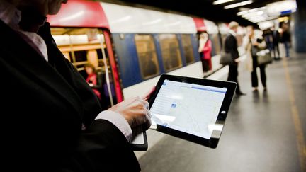 Un homme consulte internet sur sa tablette tactile, sur un quai de la ligne du RER A, &agrave; Paris, le 4 octobre 2012. ( MAXPPP)