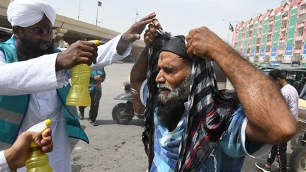 Un homme se couvre la tête d'une serviette humide pour se protéger de la chaleur, le 1er mai 2022 à Karachi (Pakistan). (SABIR MAZHAR / ANADOLU AGENCY / AFP)