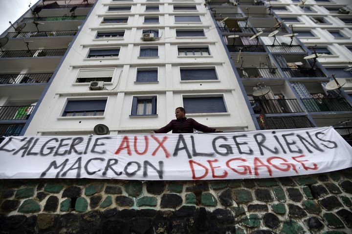 Un manifestant algérien pose devant une banderole, le 26 mars 2019, à&nbsp;Bejaïa. (RYAD KRAMDI / AFP)