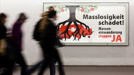 Des passants devant une affiche &eacute;lectorale avant la votation "Contre l'immigration de masse",&nbsp;le 6 f&eacute;vrier 2014 &agrave; Zurich (Suisse). (MICHAEL BUHOLZER / AFP)