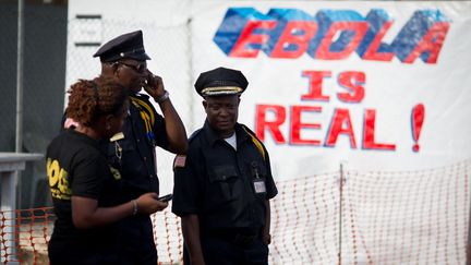 Des policiers devant une affiche de lutte contre Ebola, placard&eacute;e &agrave; proximit&eacute; du centre de traitement d'urgence du virus, &agrave; Monrovia (Liberia), le 9 avril 2015. (KAY NIETFELD / DPA / AFP)