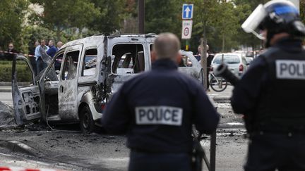 Des policiers devant une voiture de fonction brûlée à Viry-Chatillion (Essonne), le 8 octobre 2016. (THOMAS SAMSON / AFP)