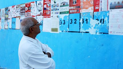 Un Tunisien observe les affiches &eacute;lectorales avec les l&eacute;gislatives, &agrave; Tunis, le 21 octobre 2014. ( CITIZENSIDE / AFP)