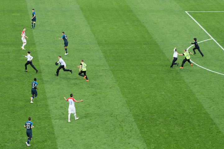 Des membres du groupe Pussy Riot courent sur la pelouse du stade Loujniki de Moscou (Russie), dimanche 15 juillet, lors de la finale de la Coupe du monde entre la France et la Croatie. (ELMAR KREMSER/ SVEN SIMON / AFP)