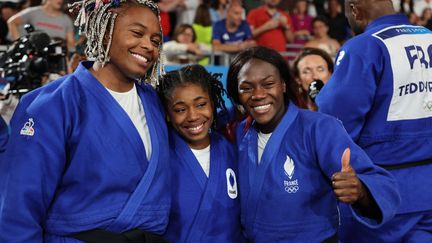 Clarisse Agnégnénou (à droite), avec Romane Dicko et Sarah Léonie Cysique (de dos, Tedy Riner), après la médaille d'or par équipe de la France en judo, samedi 3 août 2024. (JACK GUEZ / AFP)