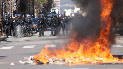 Des&nbsp;forces de l'ordre se tiennent près&nbsp;d'un feu de poubelle lors d'une manfiestation à Ajaccio (Corse du Sud), le 10 mars 2022. (PASCAL POCHARD-CASABIANCA / AFP)