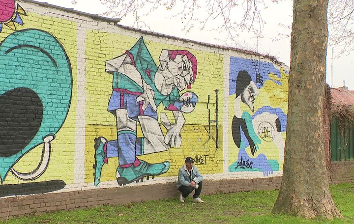 Aket devant l'une de ses œuvres en plein air : "A l'atelier, on est seul. Le mur c'est un plaisir de partage et déchanges avec les potes". (France 3 Nord Pas-de-Calais)