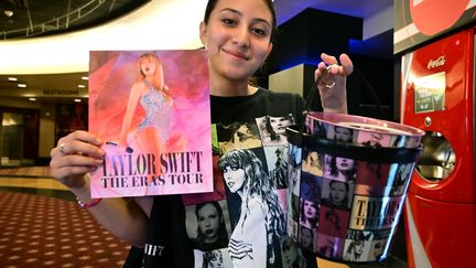 Jamie Concha, une fan de la chanteuse de Taylor Swift, tient des produits à l'éffigie de l'artiste alors qu'elle assiste à la première mondiale du film-concert "Taylor Swift : The Eras Tour" au cinéma AMC Century City à Los Angeles, Californie, le 12 octobre 2023. (FREDERIC J. BROWN / AFP)