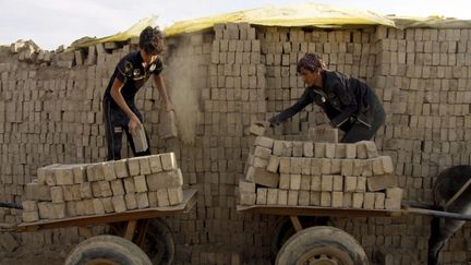 Des enfants irakiens chargent leurs charrettes de briques dans une usine près de Najaf, le 18 novembre 2018. (HAIDAR HAMDANI / AFP)