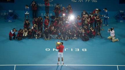 Le Serbe Novak Djokovic embrasse son troph&eacute;e devant les photographes apr&egrave;s avoir remport&eacute; l'open de tennis de Chine &agrave; P&eacute;kin, le 6 octobre 2013. (ED JONES / AFP)