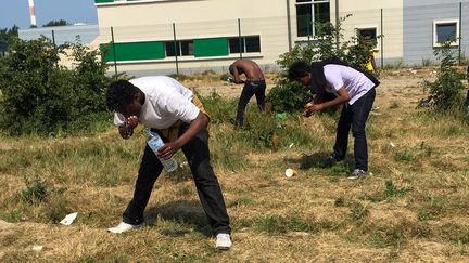 Des migrants se lavent à l'aide de bouteilles d'eau, le 21 juin 2017 à Calais.&nbsp; (DENIS CHARLET / AFP)