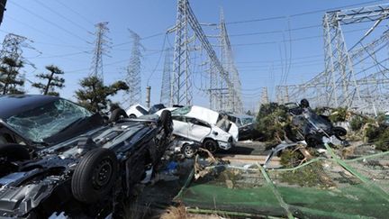 Des voitures jetées par le tsunami aux pieds d'installations électriques, dans la préfecture de Miyagi, le 13 mars 2011. (AFP PHOTO / MIKE CLARKE)