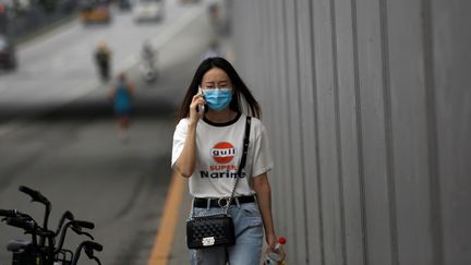 Téléphone à l'oreille, une femme marche dans les rues de Pékin (Chine), le 13 juillet 2020. (TINGSHU WANG / REUTERS)