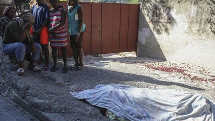 Des habitants se rassemblent devant une personne qui, selon eux, a été tuée lors d'une attaque perpétrée par des membres d'un gang, dans le quartier de Pétion-Ville à Port-au-Prince (Haïti) - 19/11/2024. (Odelyn Joseph / AP)