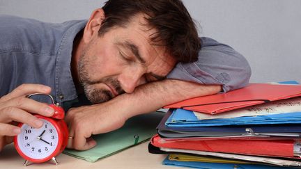 Homme endormi au travail sur son bureau. (RICHARD VILLALON / MAXPPP)