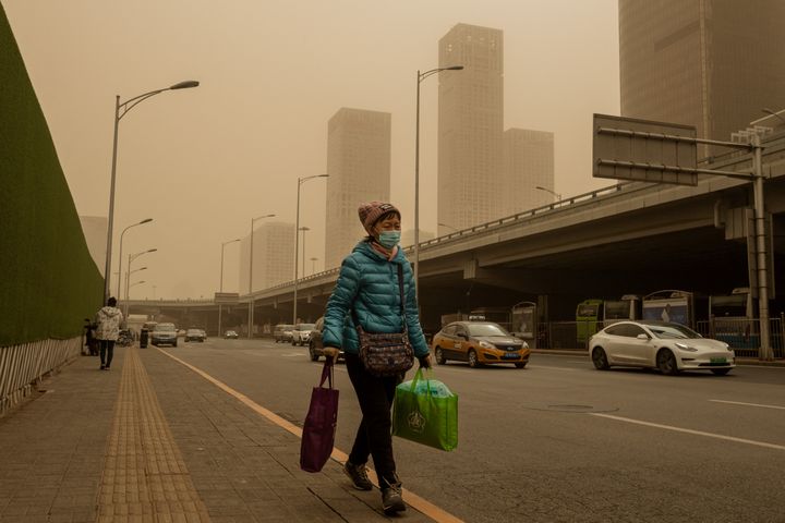 Une passante dans une rue de Pékin, le 15 mars 2021. (NICOLAS ASFOURI / AFP)