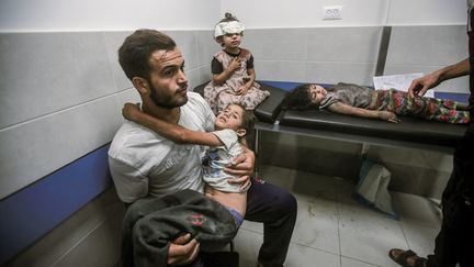 Un père et ses enfants, blessés, sont venus chercher secours à l'hôpital Al-Shifa après des attaques israéliennes sur la bande de Gaza, le 11 octobre 2023. (MOHAMED ZAANOUN / MIDDLE EAST IMAGES / AFP)