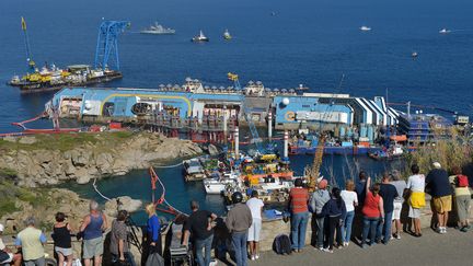 Des touristes observent l'op&eacute;ration de redressement du Costa Concordia, le 16 septembre 2013 sur l'&icirc;le du Giglio (Italie). (VINCENZO PINTO / AFP)