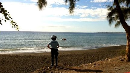 Un gendarme observe la plage de l'&icirc;le de La R&eacute;union o&ugrave; une adolescente est morte tu&eacute;e par un requin, le 15 juillet 2013. (H.DEBEUX / REUNION 1ERE)