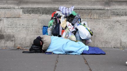 Un mendiant couché dans un sac de couchage dans la rue avec derrière lui ses affaires à Paris. (NATHANAEL CHARBONNIER / RADIO FRANCE)