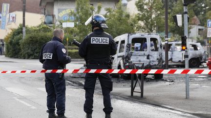 Des policiers ont installé un périmètre de sécurité devant le véhicule des policiers brûlé par des cocktails Molotov, le 8 octobre 2016, à Viry-Châtillon (Essonne). (THOMAS SAMSON / AFP)