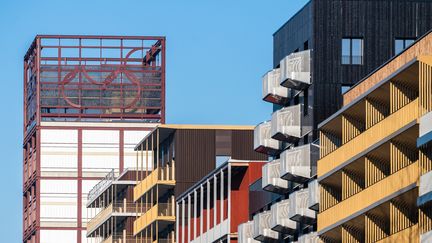 Cet immeuble, qui donne sur la place olympique, supporte, à 50 mètres de haut, l'une des quatorze œuvres d'art exposées dans le village. "Lucerna" est une œuvre signée par l’atelier CH.V, l’architecte et artiste Charlotte Vergely et le scénographe urbain Archibald Verney-Carron. Elle représente les anneaux olympiques destructurés. (SOLIDEO - Sennse -Cyril Badet)