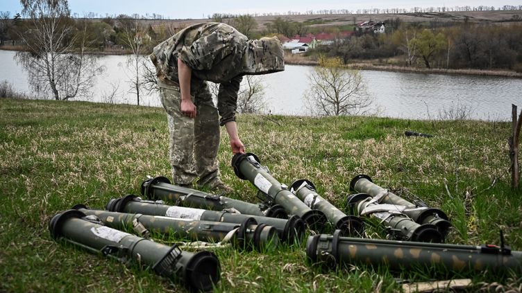 Un soldat ukrainien examine des éléments d'armement sur une ancienne position russe, dans le nord de la région de Kharkiv, le 11 avril 2023. (SERGEY BOBOK / AFP)