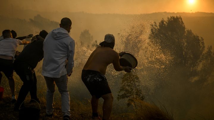 Des habitants du village de Zambujeiro, au Portugal, tentent d'éviter la propagation d'un incendie, le 25 juillet 2023. (PATRICIA DE MELO MOREIRA / AFP)