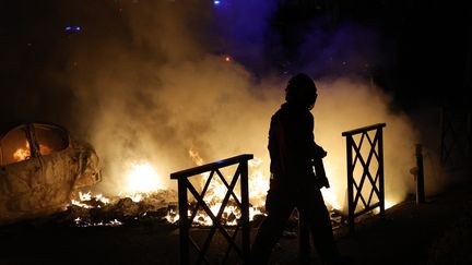 Un pompier tente d'éteindre des voitures incendiées dans la nuit du 28 au 29 juin à Nanterre, deux jours après la mort du jeune Nahel, tué par un tir de police. (GEOFFROY VAN DER HASSELT / AFP)