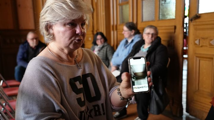 Corinne Delattre montre une photo de l'entrée de sa cave inondée en janvier, le 18 mars 2024 lors d'une permanence pour les sinistrés à Arques (Pas-de-Calais). (PAOLO PHILIPPE / FRANCEINFO)