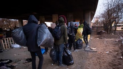 Des personnes évacuent un campement insalubre de migrants à Paris, le 31 janvier 2019. (THOMAS SAMSON / AFP)