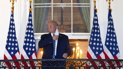 Donald Trump retire son masque sur le balcon de la Maison Blanche le 5 octobre 2020 après avoir été hospitalisé durant trois jours, contaminé par le Covid-19. (WIN MCNAMEE / GETTY IMAGES NORTH AMERICA / AFP)