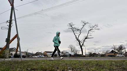 Une femme marche seule dans une rue de la grande banlieue de Kiev, en février 2024. (SERGEI SUPINSKY / AFP)