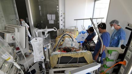 Des soignants au chevet d'un patient, le 8 mars 2021, à l'hôpital Ambroise-Paré, à Boulogne-Billancourt (Hauts-de-Seine). (ALAIN JOCARD / AFP)