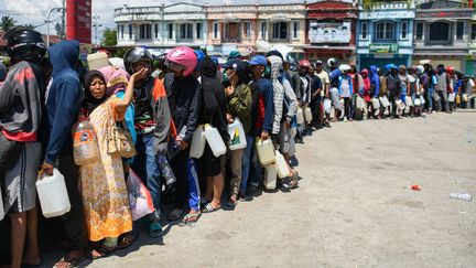 Des survivants du séisme et du tsunami qui ont frappé les Célèbes, en Indonésie, font la queue devant une station essence à Palu, une ville sur la côte ouest de l'île, le 1er octobre 2018. (JEWEL SAMAD / AFP)