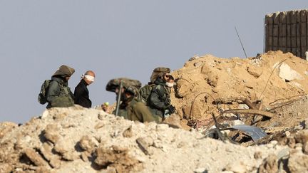 Des soldats israéliens aux côtés de Palestiniens les yeux bandés, le 19 novembre 2023 dans la bande de Gaza. (MAHMUD HAMS / AFP)