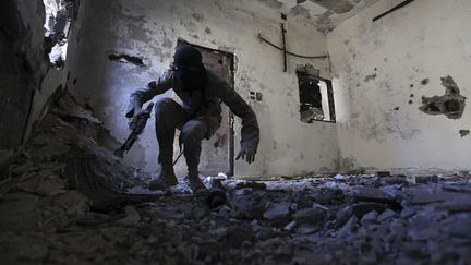 Un soldat de l'Arm&eacute;e syrienne libre se planque dans une maison en ruines &agrave;&nbsp;Deir al-Zor (Syrie), le 30 septembre 2013. (REUTERS)