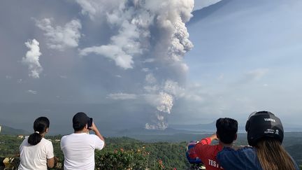 Des personnes prennent en photo l'éruption du volcan Taal, le 12 janvier 2020, près de Manille (Philippines). (BULLIT MARQUEZ / AFP)