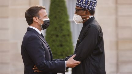 Le président français Emmanuel Macron (G) accueille&nbsp;au Palais de l'Elysée le président nigérian Muhammadu Buhari à son arrivée pour un dîner après la conférence internationale à Paris, le 17 mai 2021. (LUDOVIC MARIN / AFP)