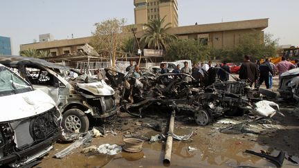 Des Baghdadis autour des restes calcin&eacute;s d'une voiture pi&eacute;g&eacute;es dans la capitale irakienne, le 7 mars 2014. (ALI AL-SAADI / AFP)