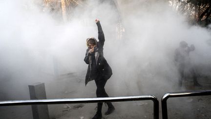 Une femme iranienne lève le poing au milieu des gaz lacrymogènes à l'université de Téhéran lors d'une manifestation de colère contre les problèmes économiques, le 30 décembre 2017. (AFP)