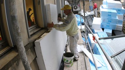 Un artisan réalise l'isolation de la façade d'un bâtiment dans le cadre de travaux de rénovation énergétique, à Auch (Gers), le 30 janvier 2018. (SEBASTIEN LAPEYRERE / MAXPPP)