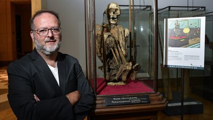 Serge Lemaitre, archéologue et&nbsp;conservateur des collections Amériques du &nbsp;MAH (Musée Art et Histoire) de Bruxelles, pose à côté de la momie présentée&nbsp; comme celle ayant insopiré Hergé pour son persoonage de Rascar Capac, dans l'album "Les 7 boules de cristal". (JOHN THYS / AFP)