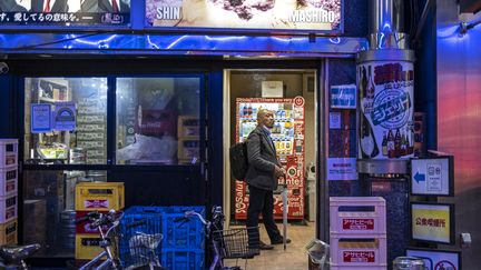 Un homme fume une cigarette à l'entrée d'un local équipé d'un distributeur automatique à Tokyo, au Japon. (CHARLY TRIBALLEAU / AFP)