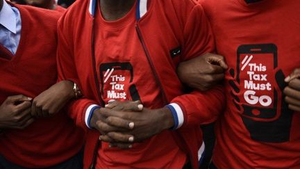 Des manifestants arborent des t-shirts où l'on peut lire «This Tax must go» (cette taxe doit disparaître), lors d'une manifestation le 11 juillet 2018 à Kampala. Ils protestent contre la taxe sur les réseaux sociaux instaurée en Ouganda. Le slogan est né d'un hashtag éponyme sur les réseaux sociaux.  (ISAAC KASAMANI / AFP)