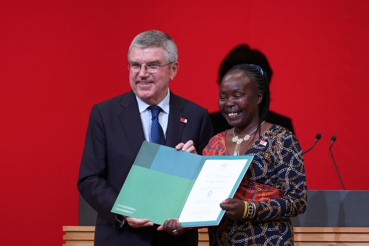 Le 24 juillet 2019, à Tokyo, avant le début de la pandémie, Tegla Loroupe, chef de mission pour l'équipe olympique des réfugiés présente l'invitation officielle pour les JO de Tokyo, ici aux côtés du président du CIO, Thomas Bach. (BEHROUZ MEHRI / AFP)