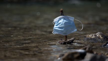 Un petit bateau fait de morceaux de bois,&nbsp;avec pour voile un masque chirurgical, flotte sur un cours d'eau à Briançon (Hautes-Alpes), le 23 avril 2021. (THIBAUT DURAND / AFP)